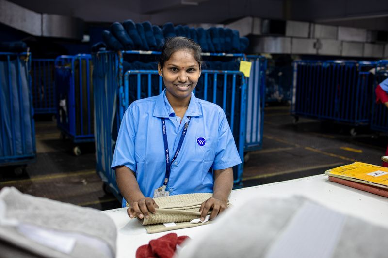 A smiling factory worker folding textiles